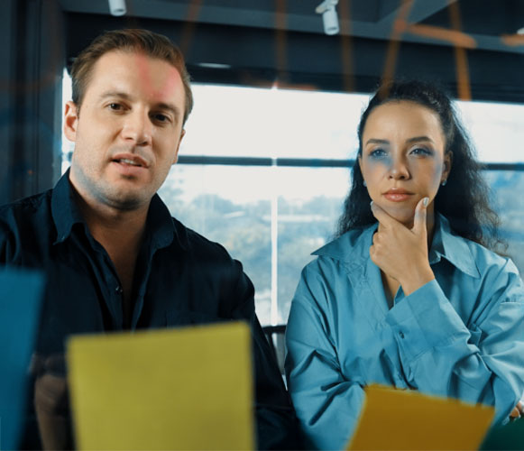 dos personas pensando ideas con papeles pegados a un cristal