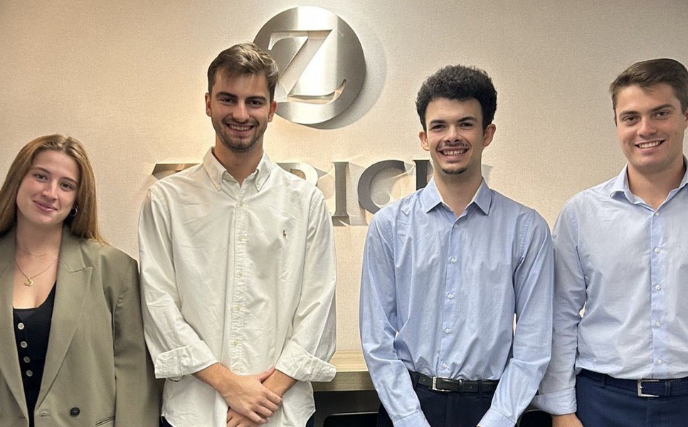 4 jóvenes sonrientes, mirando a cámara en las oficinas Zurich